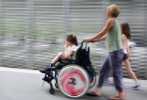 Mutter mit Kind im Rollstuhl unterwegs