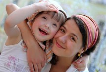 Mutter mit Tochter auf dem Arm, glücklich lächelnd