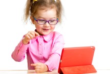 Kind am Tisch vor kleinem Computer Display.