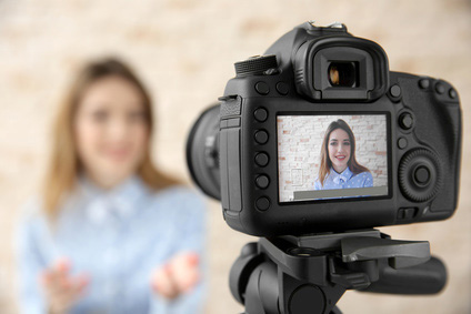 Kamera mit Bild der Aufnahme, die im Hintergrund eine junge Frau zeigt, die sich filmt